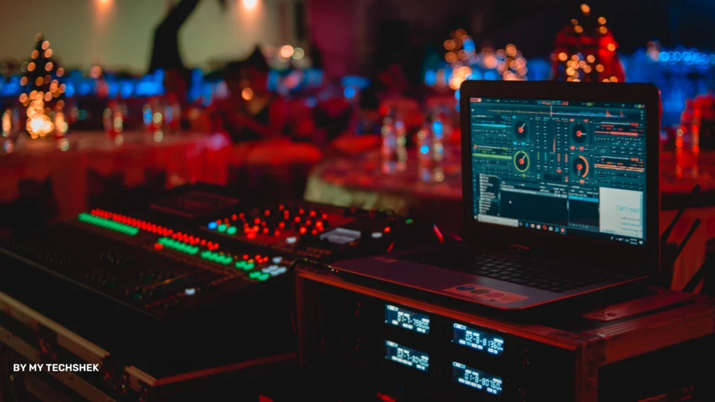 a laptop on a table with a sound board and other equipment